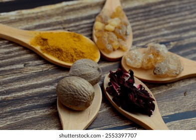 A kitchen studio food shot of various spices (Turmeric, Nutmeg, Hibiscus, Frankincense and Acacia) in a wooden spoons isolated on a wooden background. - Powered by Shutterstock - Get 15% off with code: PIKWIZARD15
