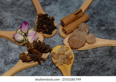 A kitchen studio food shot of various spices (Turmeric, Nutmeg, Hibiscus, Frankincense and Acacia) in a wooden spoons isolated on a wooden background. - Powered by Shutterstock