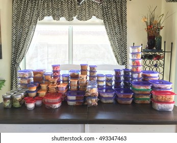 Kitchen Table Filled With Stacks Of Prepared Food Storage Containers.