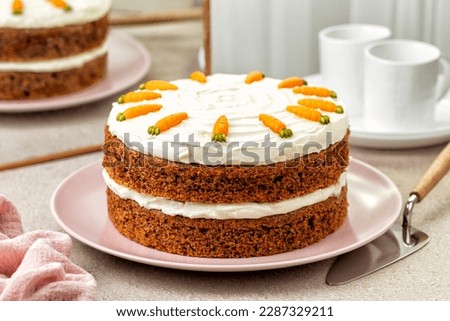 Kitchen table with homemade carrot cake made with walnuts, iced with cream cheese. Sweet dessert. White marble background.