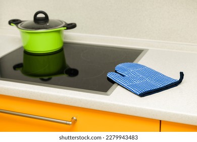 kitchen tack glove lies on the stove. kitchen potholder lies near the hob in the kitchen. oven mitt is in the kitchen.