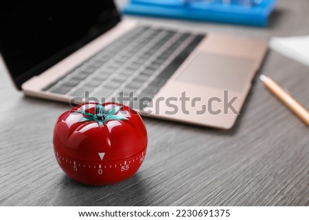 Kitchen timer in shape of tomato and laptop on wooden table, space for text
