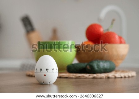 Kitchen timer and vegetables on table in room, closeup