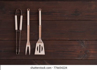 kitchen tongs, fork for meat and spatula on a wooden background
