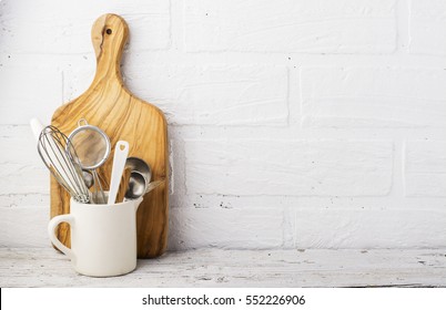 Kitchen tools, olive cutting board on a kitchen shelf against a white brick wall. Selective focus 