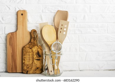 Kitchen tools, olive cutting board on a kitchen shelf against a white brick wall. selective focus.