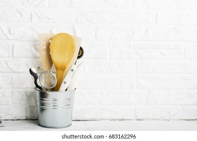 Kitchen tools, olive cutting board on a kitchen shelf against a white brick wall. selective focus.