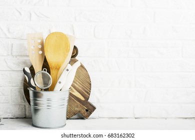 Kitchen tools, olive cutting board on a kitchen shelf against a white brick wall. selective focus.