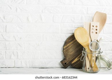 Kitchen tools, olive cutting board on a kitchen shelf against a white brick wall. selective focus.