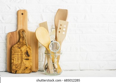 Kitchen tools, olive cutting board on a kitchen shelf against a white brick wall. selective focus.