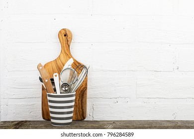 Kitchen tools, olive cutting board on a kitchen shelf against a white brick wall. selective focus.