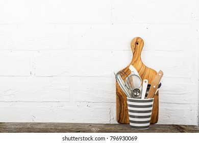 Kitchen tools, olive cutting board on a kitchen shelf against a white brick wall. selective focus.