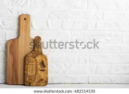 Kitchen tools, olive cutting board on a kitchen shelf against a white brick wall. selective focus.