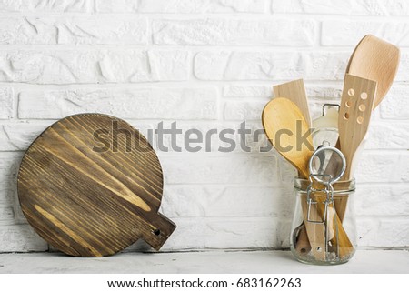 Kitchen tools, olive cutting board on a kitchen shelf against a white brick wall. selective focus.