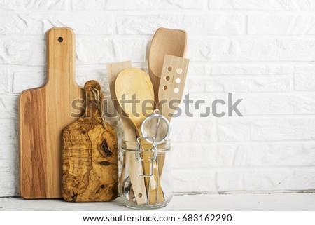 Kitchen tools, olive cutting board on a kitchen shelf against a white brick wall. selective focus.
