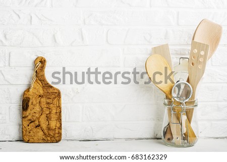 Kitchen tools, olive cutting board on a kitchen shelf against a white brick wall. selective focus.