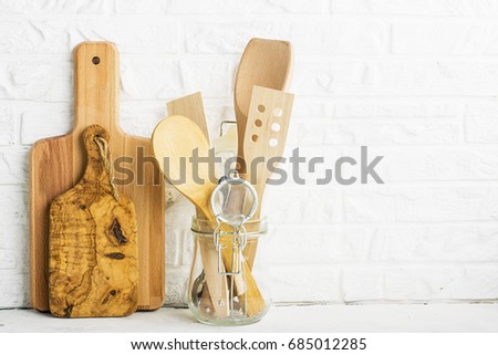 Kitchen tools, olive cutting board on a kitchen shelf against a white brick wall. selective focus.