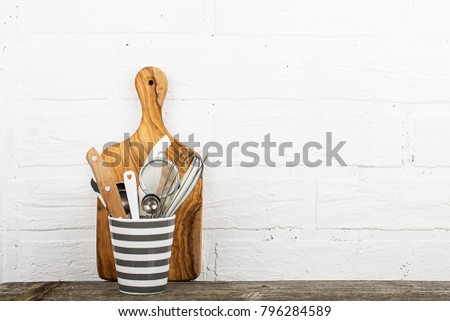 Kitchen tools, olive cutting board on a kitchen shelf against a white brick wall. selective focus.