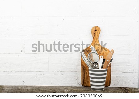Kitchen tools, olive cutting board on a kitchen shelf against a white brick wall. selective focus.