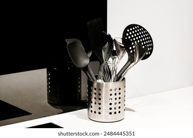 Kitchen utensils in containers in kitchen. Strainer Spoon, Spaghetti Server, Slotted Tourner, Salad Fork Spoon, Spatula, Metallic Spoon. Various types of spoons made of metal or non-stick plastic used - Powered by Shutterstock