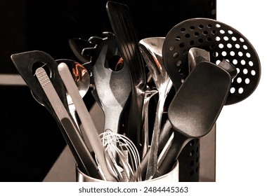 Kitchen utensils in containers in kitchen. Strainer Spoon, Spaghetti Server, Slotted Tourner, Salad Fork Spoon, Spatula, Metallic Spoon. Various types of spoons made of metal or non-stick plastic used - Powered by Shutterstock