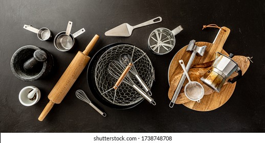 Kitchen utensils (cooking tools) on black chalkboard background - horizontal banner layout. Kitchenware collection captured from above (top view, flat lay).