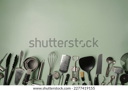 Kitchen utensils or cooking tools on green background, top view, flat lay. Kitchenware collection with copy space. Cooking background.