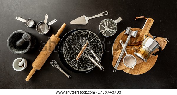 Kitchen utensils (cooking\
tools) on black chalkboard background - horizontal banner layout.\
Kitchenware collection captured from above (top view, flat\
lay).