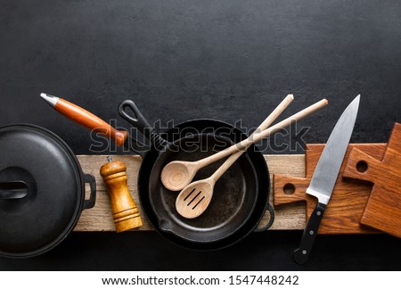 Kitchen utensils dark background with cast iron black kitchenware, top down view, blank space for a text