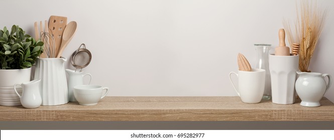 Kitchen utensils and dishware on wooden shelf