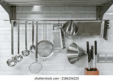 Kitchen utensils hanging on white tiled background.  - Powered by Shutterstock