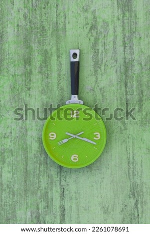 kitchen wall clock on green wooden background