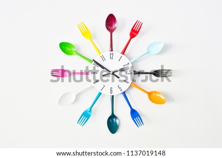A kitchen wall colorful clock, decorated with bright tableware: spoons and forks