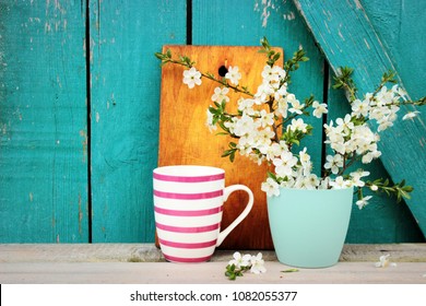 Kitchen ware set on bright turquoise wooden background, vintage crockery, chopping board and beautiful spring bouquet in a simple case, rustic design. Shabby chic