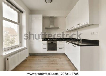 a kitchen with white cupboards and black counter tops on the floor in front of the window looking out onto the street