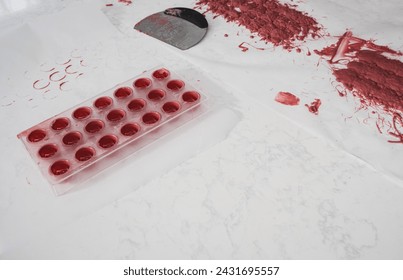 Kitchen work surface. Pink chocolate is poured into a plastic mold. Thickened chocolate spill.
