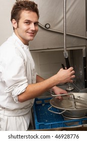 Kitchen Worker Washing Up In Restaurant Kitchen