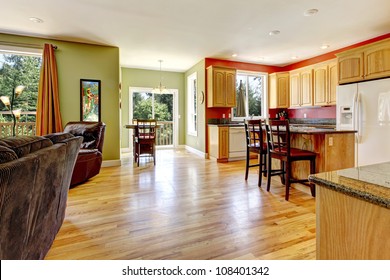 Kitchen With Yellow Wood Floor And Green Wall Near Living Room.