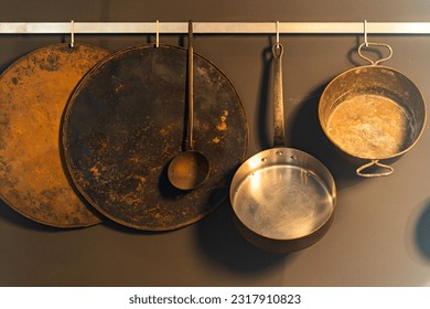 Kitchenware, pans on the metal wall of a kitchen. - Shutterstock ID 2317910823