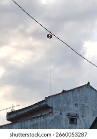 Kite string spool caught on wire above the rooftop.