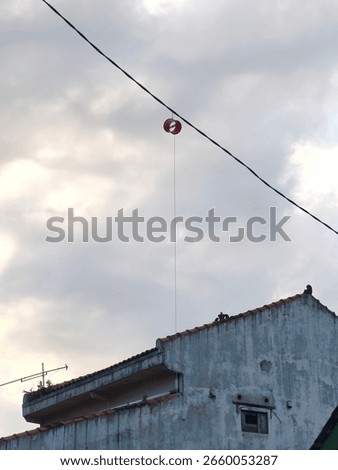 Kite string spool caught on wire above the rooftop.