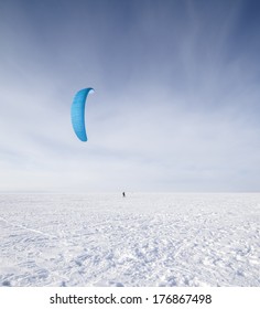 Kite surfer being pulled by his kite across the snow