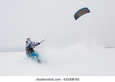 Kite surfer being pulled by his kite across the snow