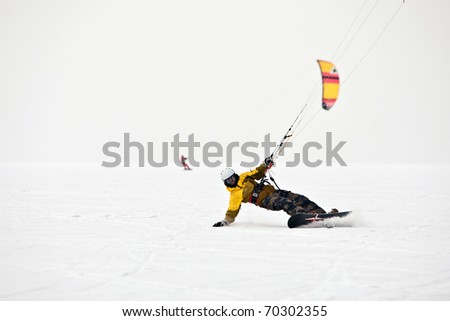 Kite surfer ride on snowboard. Snowkiting in the snow on frozen lake.