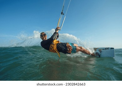Kite surfer riding a kiteboard on the sea with splash