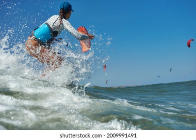 Kite Surfer Woman Jumps With Kiteboard  In Transition And Throws Up The Board