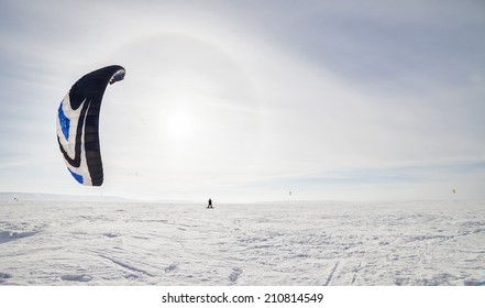 Kiteboarder With Blue Kite On The Snow