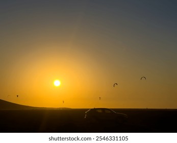 Kitesurfers Enjoy the Sunset at the Beach While a Car Silhouettes in the Foreground During a Warm Evening - Powered by Shutterstock