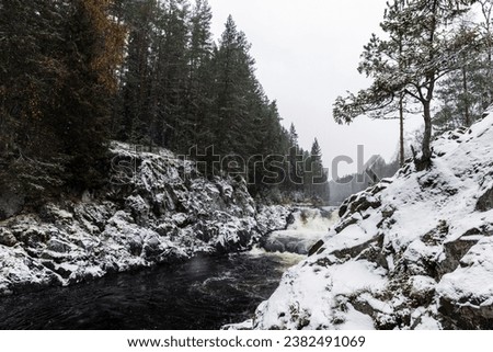 Kivach Falls on a cold cloudy winter day. Landscape with snowy cascade waterfall. Suna River, Kondopoga District, Republic of Karelia, Russia