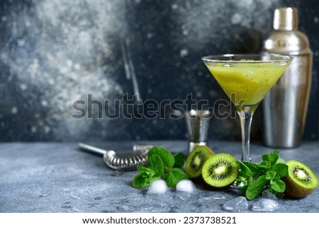 Kiwi cocktail with mint in a martini glasses on dark slate, stone or concrete background .